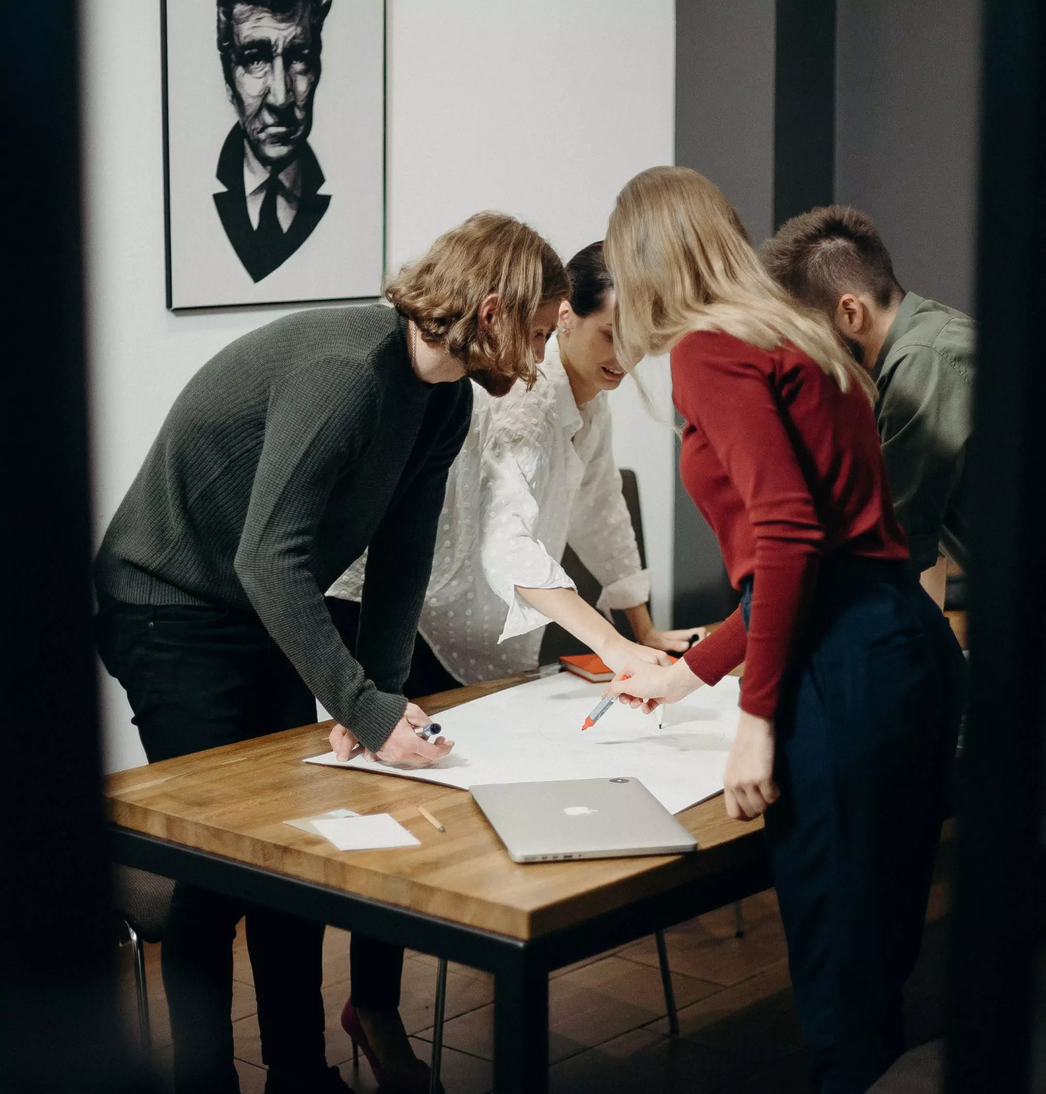 Grupa osób pisząca na dużej kartce papieru położonej na stole